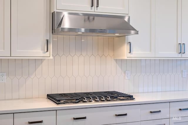 kitchen featuring exhaust hood, light countertops, white cabinetry, stainless steel gas stovetop, and tasteful backsplash