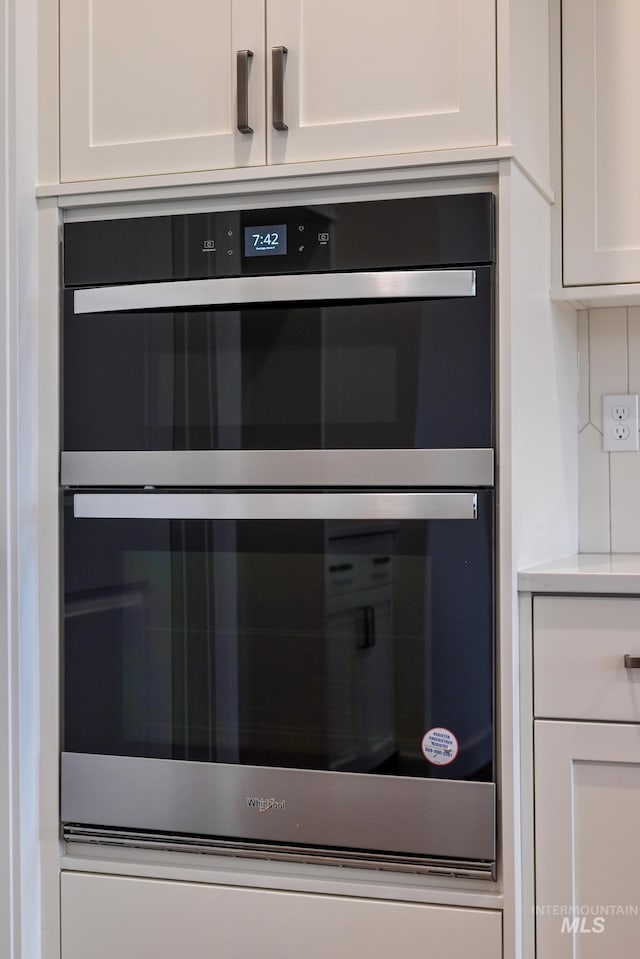 interior details with light countertops, multiple ovens, and white cabinets