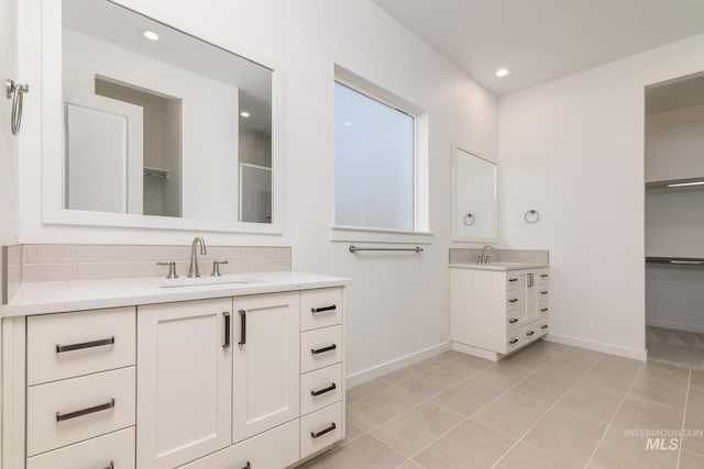 bathroom with baseboards, two vanities, and a sink
