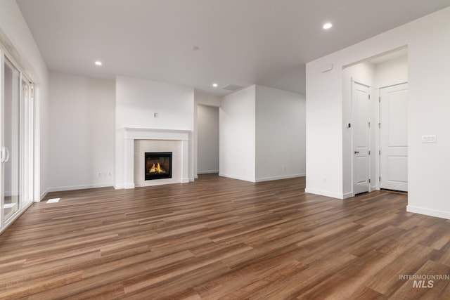 unfurnished living room with a glass covered fireplace, baseboards, recessed lighting, and wood finished floors