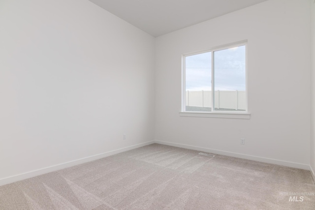spare room with baseboards and light carpet