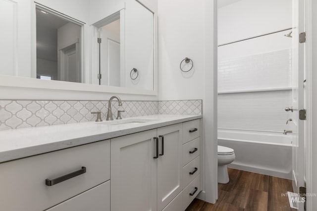 full bathroom with shower / bath combination, decorative backsplash, wood finished floors, vanity, and toilet