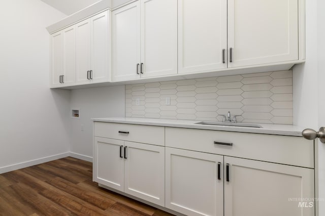 clothes washing area with washer hookup, cabinet space, a sink, baseboards, and dark wood-type flooring
