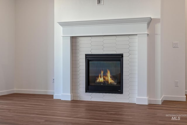 room details featuring baseboards, a brick fireplace, wood finished floors, and visible vents