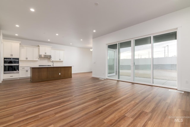 unfurnished living room featuring baseboards, recessed lighting, wood finished floors, and visible vents