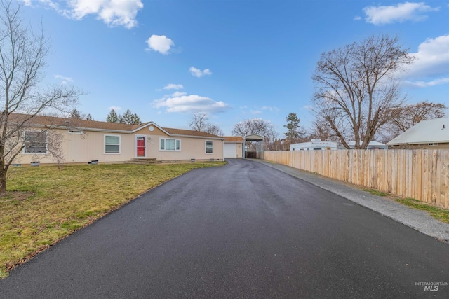 view of front of property featuring aphalt driveway, a front yard, and fence