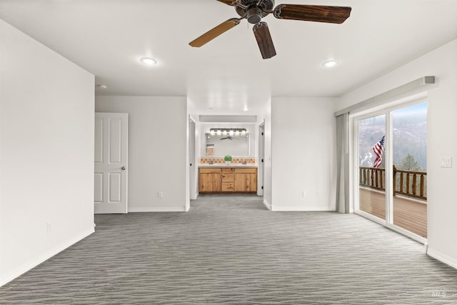 unfurnished living room featuring ceiling fan and dark colored carpet