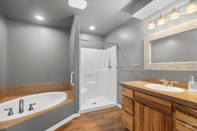 bathroom with wood-type flooring, shower with separate bathtub, and vanity