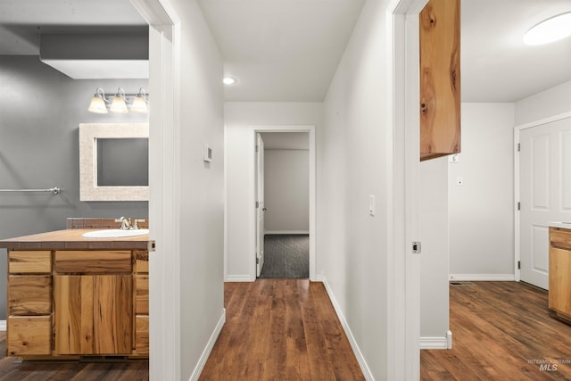 corridor with dark hardwood / wood-style flooring and sink