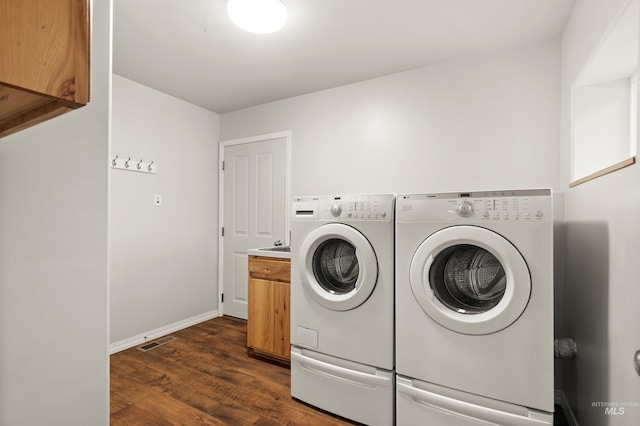 clothes washing area featuring cabinets, washer and dryer, and dark wood-type flooring