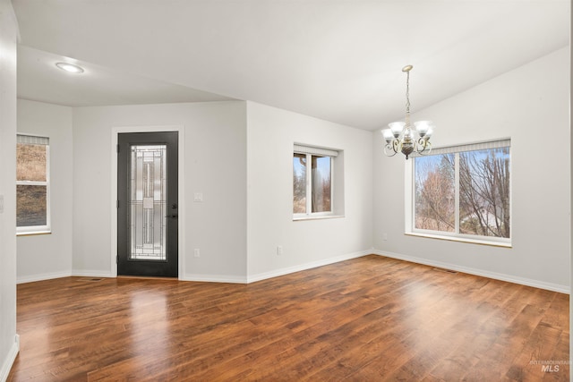 interior space featuring a notable chandelier, hardwood / wood-style flooring, and vaulted ceiling