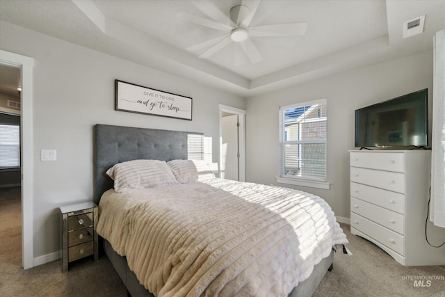 carpeted bedroom featuring ceiling fan and a tray ceiling