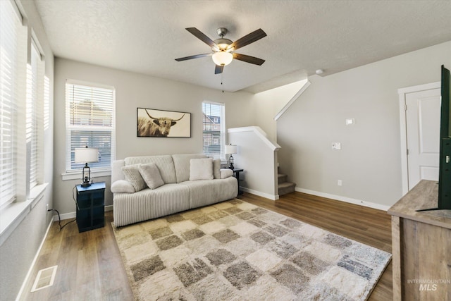 living room with ceiling fan, hardwood / wood-style flooring, a wealth of natural light, and a textured ceiling