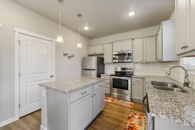 kitchen featuring sink, decorative light fixtures, a center island, light hardwood / wood-style flooring, and appliances with stainless steel finishes