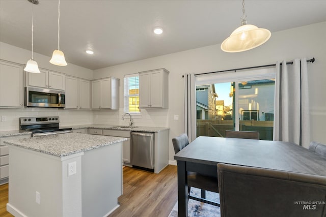 kitchen featuring stainless steel appliances, tasteful backsplash, a center island, and decorative light fixtures