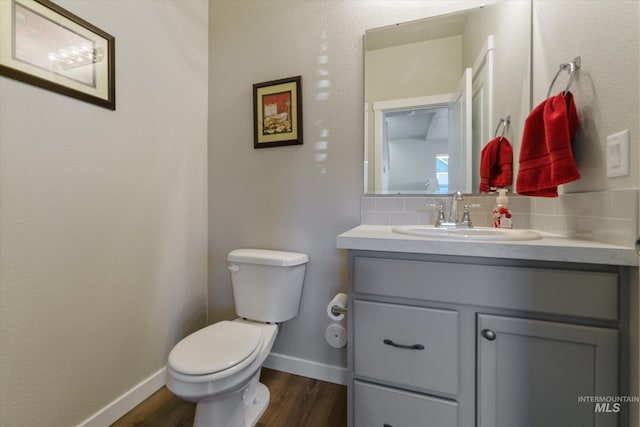 bathroom with tasteful backsplash, vanity, toilet, and hardwood / wood-style floors