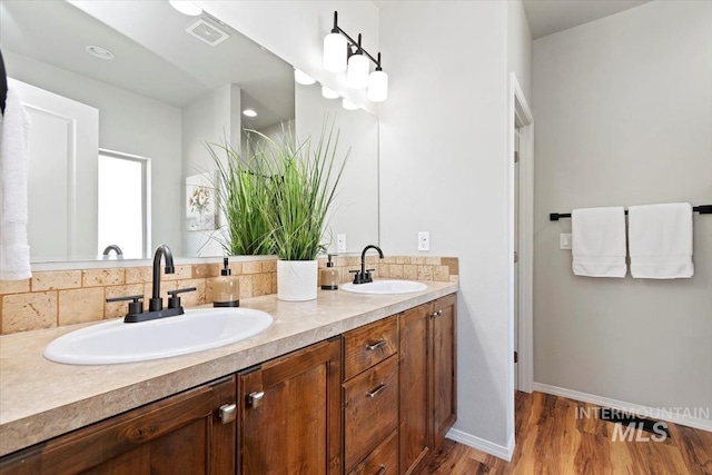 full bathroom with wood finished floors, decorative backsplash, double vanity, and baseboards