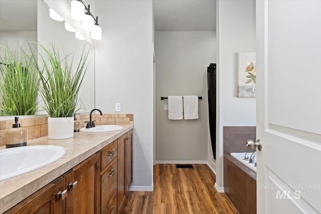 full bath with wood finished floors, double vanity, a bath, baseboards, and a shower