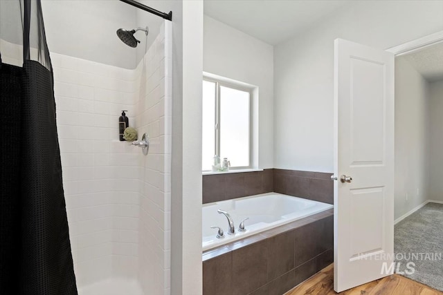 bathroom featuring a stall shower, wood finished floors, and a bath