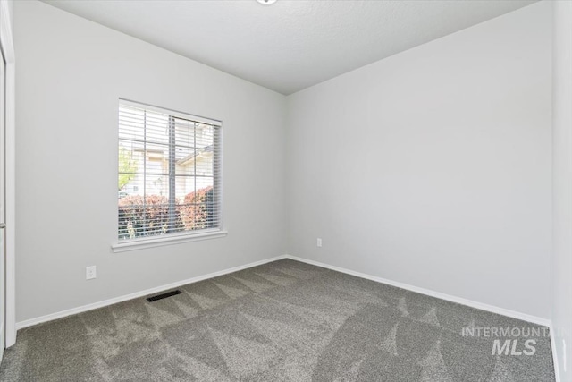empty room featuring carpet and baseboards