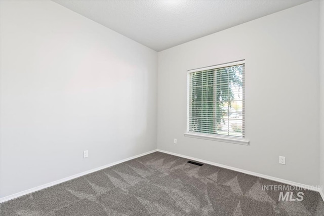 unfurnished room with dark carpet, baseboards, and a textured ceiling