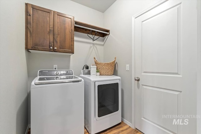 laundry room with independent washer and dryer, cabinet space, light wood-style flooring, and baseboards