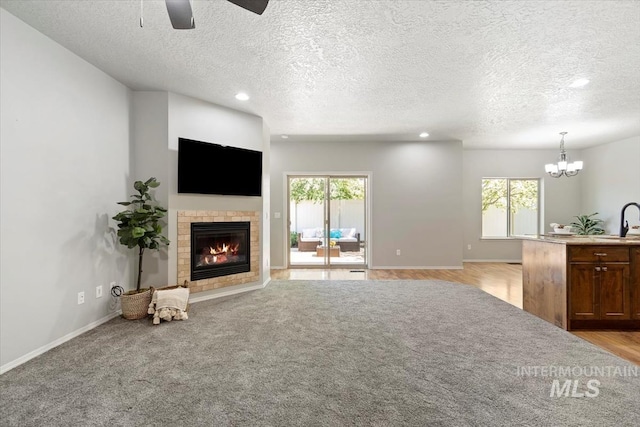 unfurnished living room featuring a tiled fireplace, a textured ceiling, ceiling fan, healthy amount of natural light, and recessed lighting