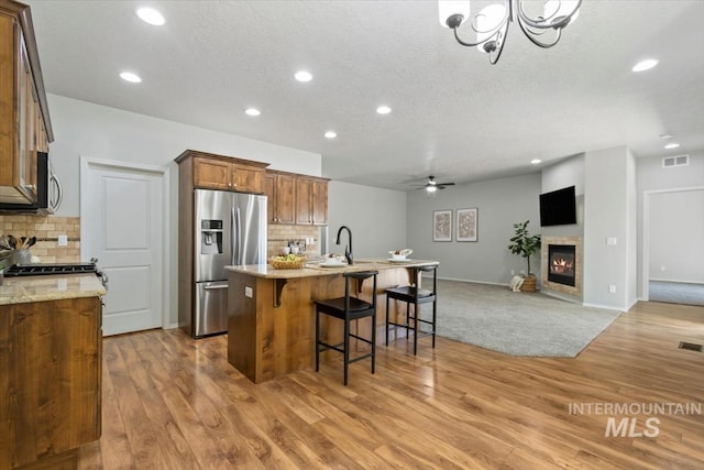 kitchen featuring appliances with stainless steel finishes, open floor plan, tasteful backsplash, recessed lighting, and light wood-style flooring