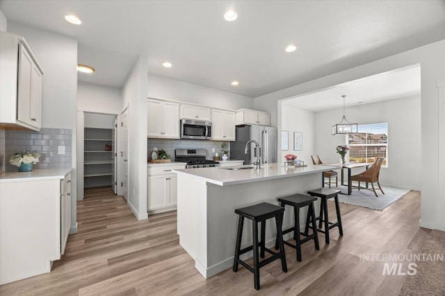 655 N Sevenoaks Ave, Eagle, ID 83616 - kitchen with stainless steel appliances, decorative backsplash, a breakfast bar, light wood finished floors, and recessed lighting