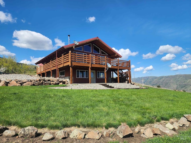 back of house with a lawn and a deck with mountain view