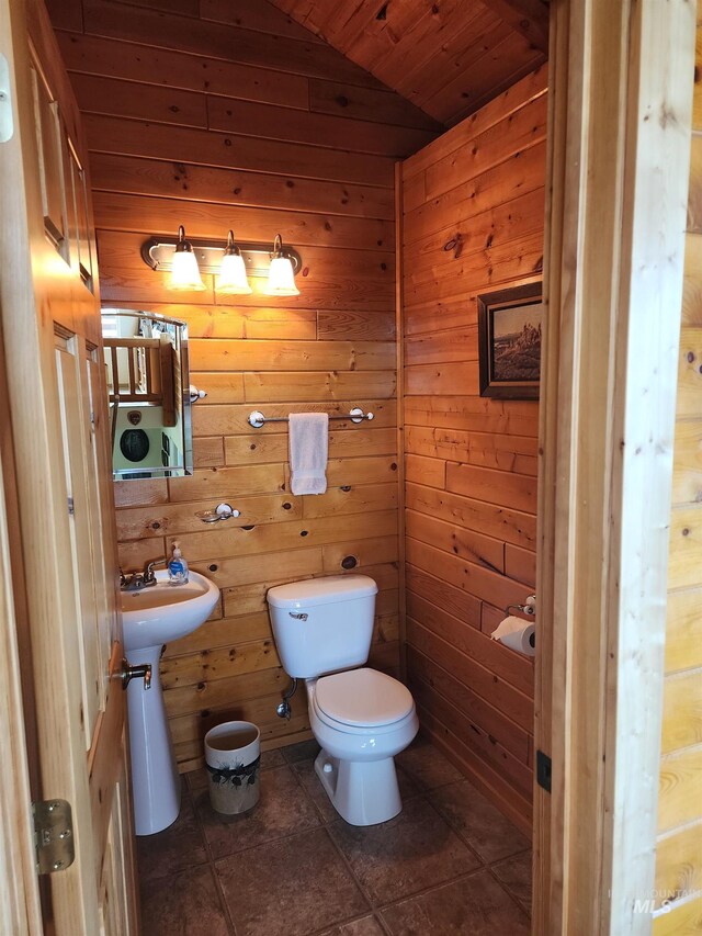 bathroom featuring wood walls, lofted ceiling, tile patterned floors, and toilet
