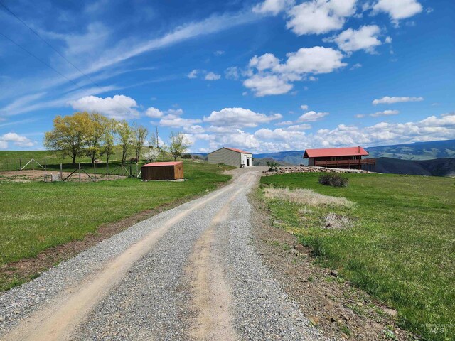 view of street featuring a rural view, a pole building, and gravel driveway
