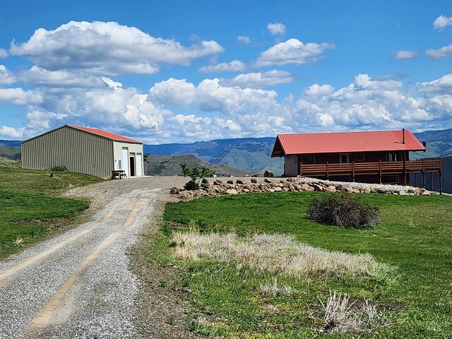 view of road with a mountain view and gravel driveway