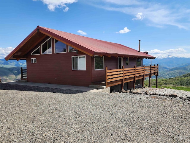 view of side of home with a deck with mountain view and metal roof