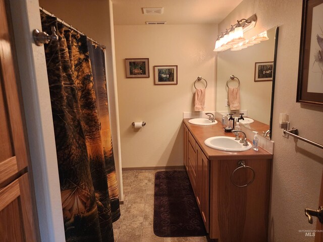 bathroom featuring a sink, tile patterned floors, double vanity, and visible vents