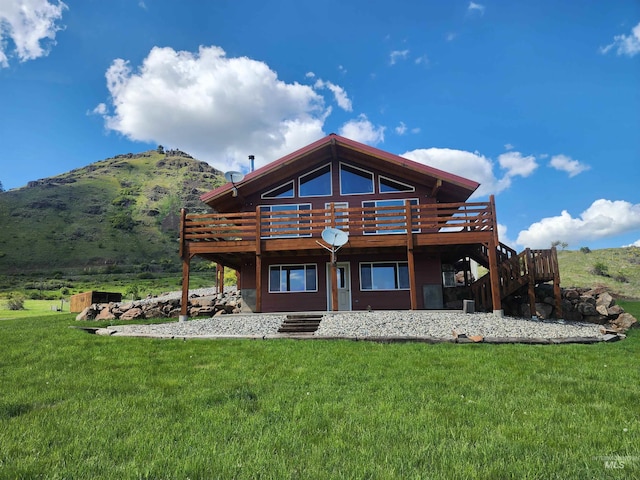 back of property featuring a yard, a deck with mountain view, and stairway