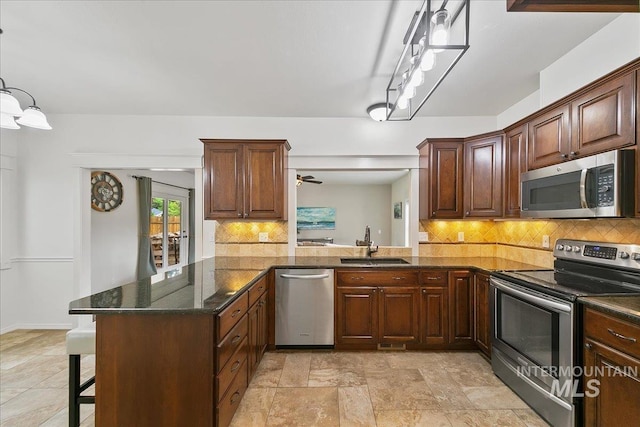 9874 W Whirlaway Ct, Boise, ID 83704 - kitchen with appliances with stainless steel finishes, a sink, tasteful backsplash, a breakfast bar, and dark stone countertops