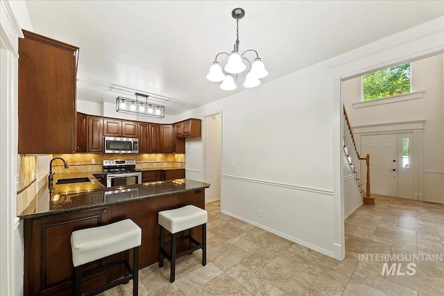 9874 W Whirlaway Ct, Boise, ID 83704 - kitchen with appliances with stainless steel finishes, a peninsula, tasteful backsplash, a chandelier, and stone finish flooring
