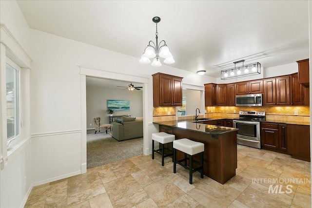 9874 W Whirlaway Ct, Boise, ID 83704 - kitchen featuring appliances with stainless steel finishes, a sink, a chandelier, decorative backsplash, and light stone finish floors