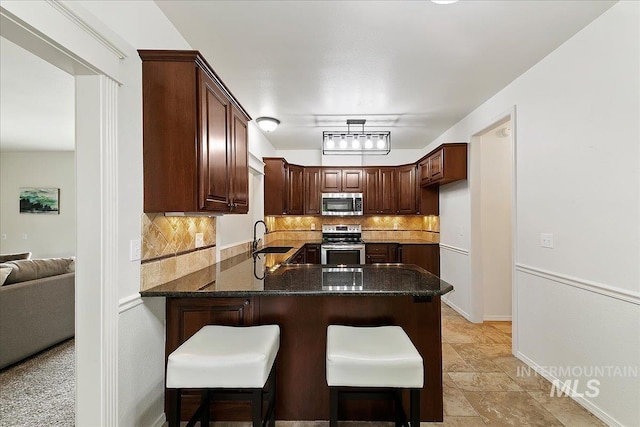 9874 W Whirlaway Ct, Boise, ID 83704 - kitchen with stainless steel appliances, tasteful backsplash, a peninsula, a sink, and dark stone countertops