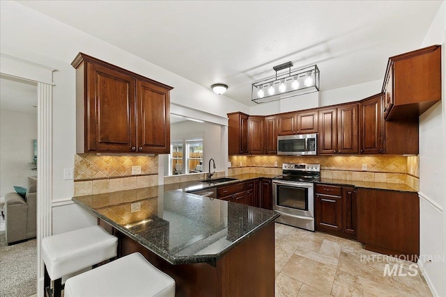 9874 W Whirlaway Ct, Boise, ID 83704 - kitchen with appliances with stainless steel finishes, a sink, tasteful backsplash, a kitchen bar, and a peninsula