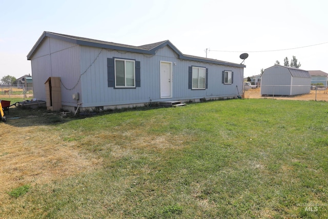 back of house featuring a yard and an outdoor structure