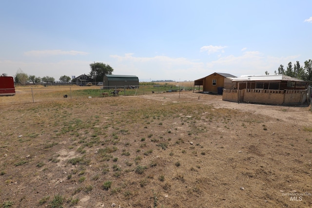 view of yard with fence, an outbuilding, and a rural view