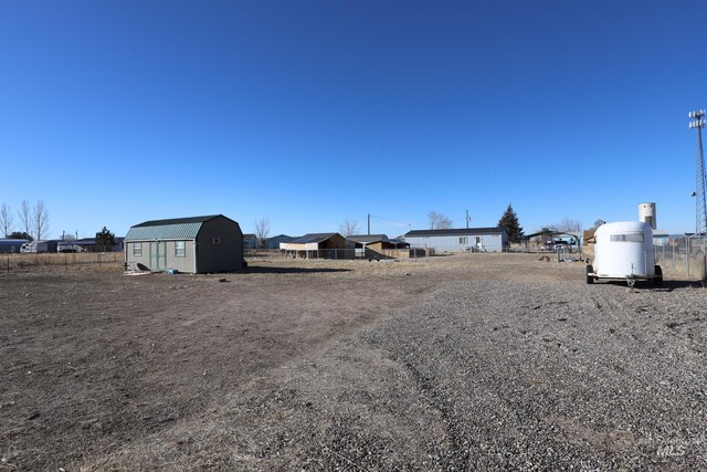view of yard featuring a storage shed, fence, and an outdoor structure