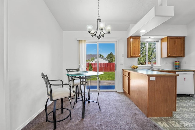 7842 Arlington Dr, Nampa, ID 83687 - kitchen with white dishwasher, a chandelier, brown cabinetry, light carpet, and plenty of natural light