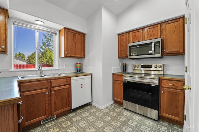 7842 Arlington Dr, Nampa, ID 83687 - kitchen with stainless steel appliances, a sink, brown cabinets, and baseboards