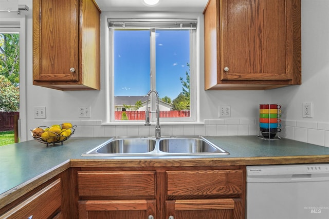 7842 Arlington Dr, Nampa, ID 83687 - kitchen with white dishwasher, a sink, brown cabinetry, and dark countertops