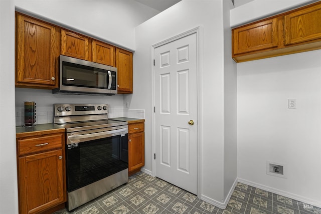 7842 Arlington Dr, Nampa, ID 83687 - kitchen featuring stainless steel appliances, brown cabinets, baseboards, and tile patterned floors