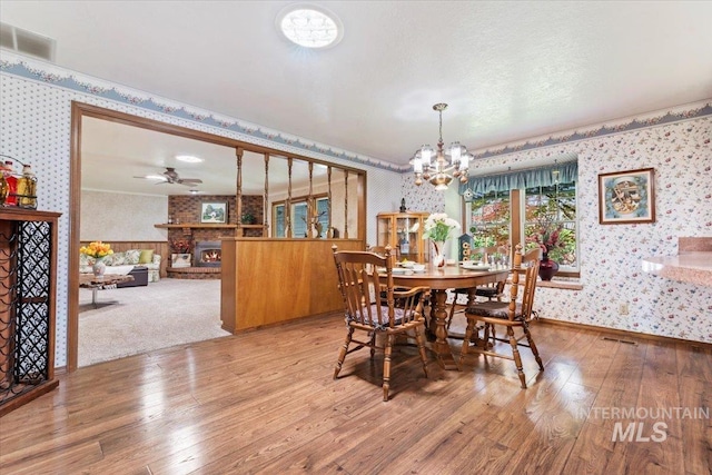 3428 N Columbine Ave, Boise, ID 83713 - dining room with wallpapered walls, light wood-style floors, a chandelier, a fireplace, and baseboards