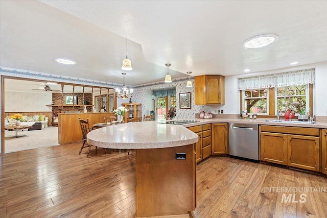 3428 N Columbine Ave, Boise, ID 83713 - kitchen with stainless steel dishwasher, wallpapered walls, a peninsula, brown cabinets, and light wood-style flooring